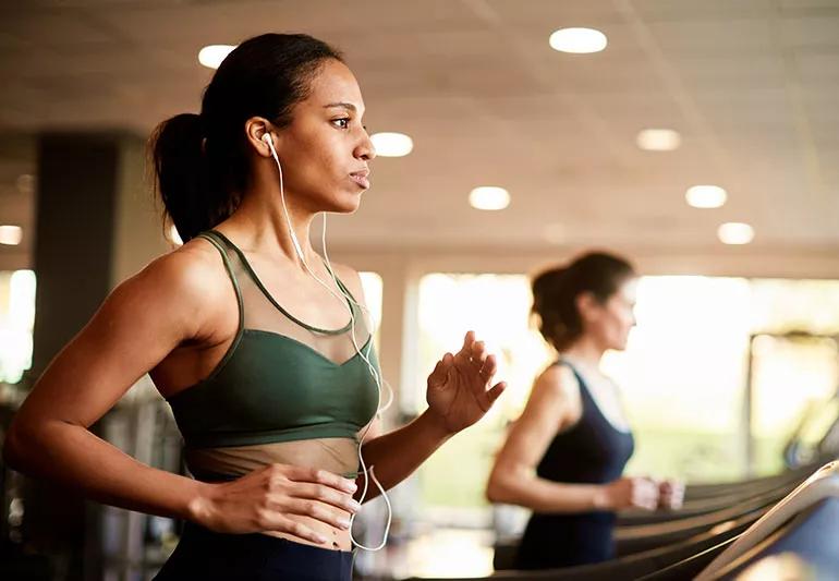 Two people running on a treadmill at the gym.