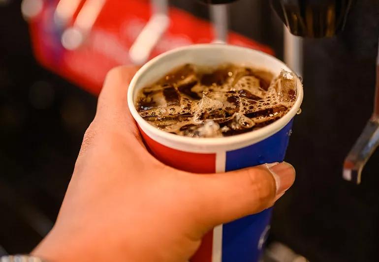 filling up cup with fructose rich fountain soda