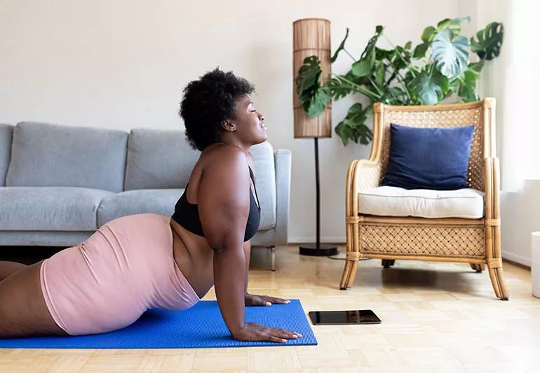 woman doing cobra yoga pose in her living room