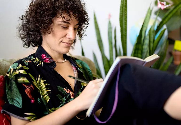 Person on couch writing in their journal to find stress relief.