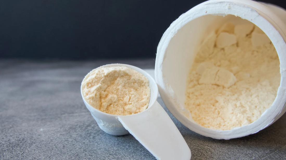 Scoop and container of bovine colostrum powder on counter