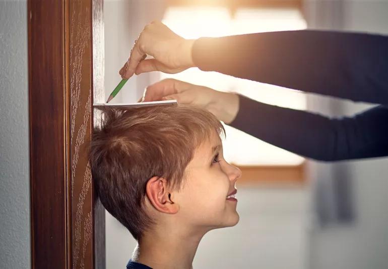 child gettin his height measured at home on wall