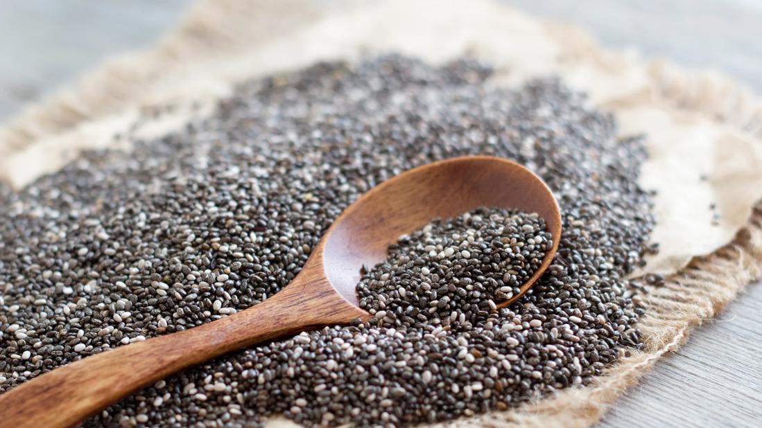 Wooden spoon of chia seeds on pile of chia seeds on piece of burlap