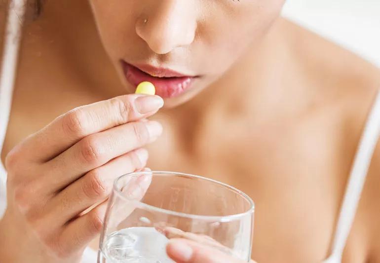 woman taking pill medicine cause metal taste