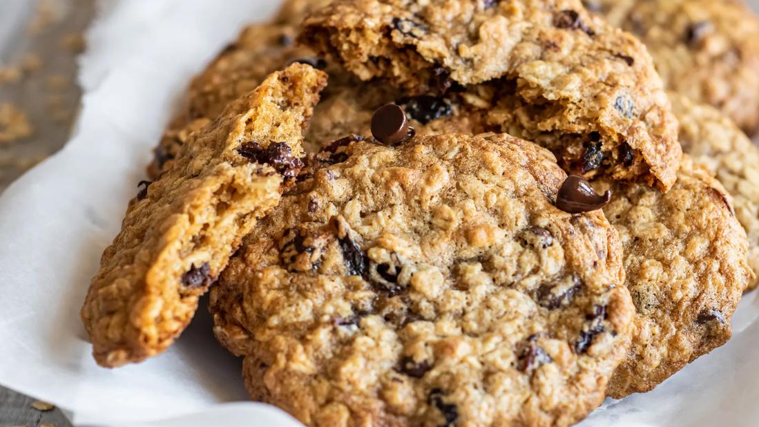 A pile of chocolate cherry oatmeal cookies sit on a napkin.