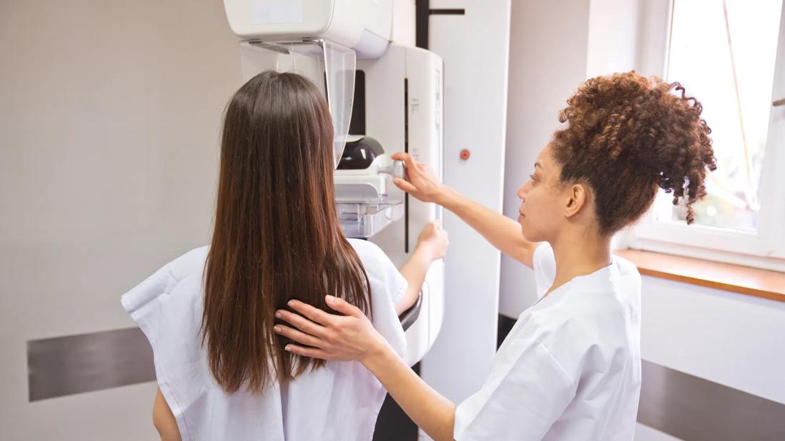 Woman receiving a mammogram, with a healthcare provider guiding