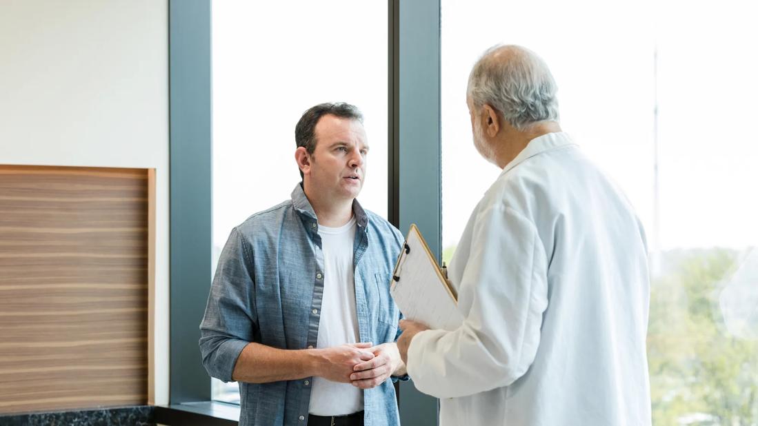 Person and healthcare provider holding clipboard standing and talking