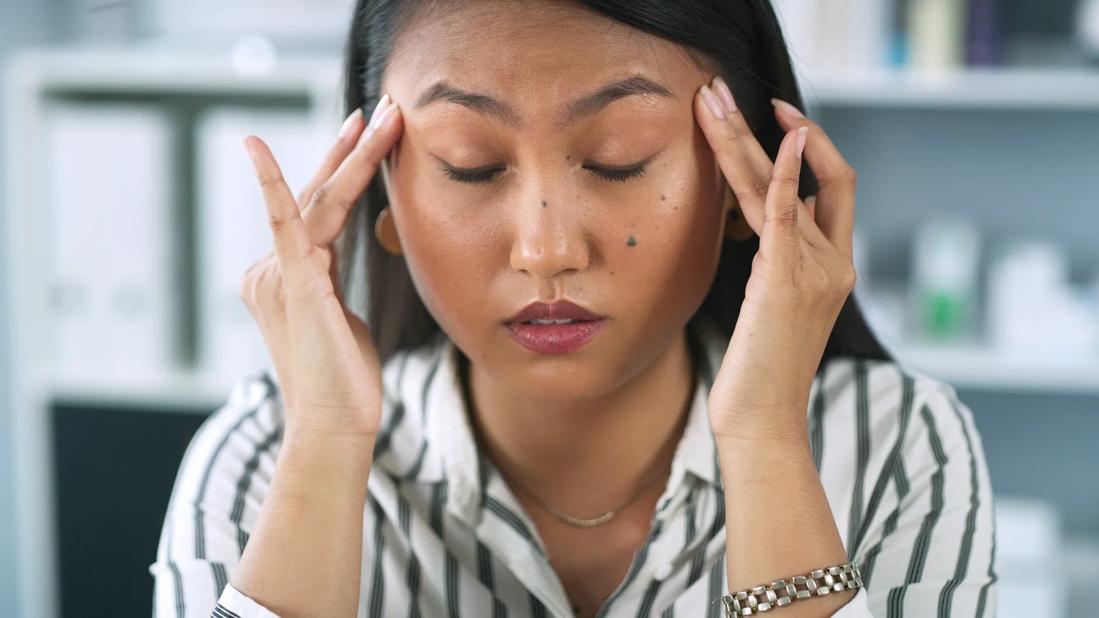 Person with eyes closed, rubbing fingers on their temples