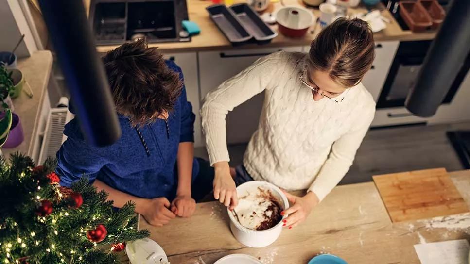 Overhead view, female and male in kitchen preparing food, christmas tree and baking pans