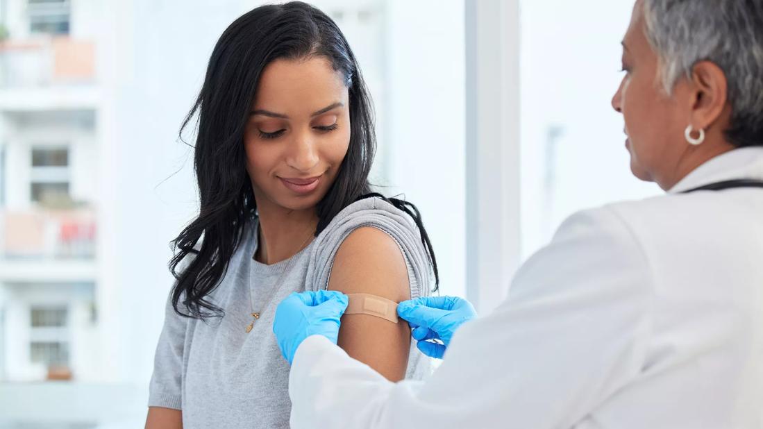 Healthcare provider apply bandaid on patient's arm after a shot