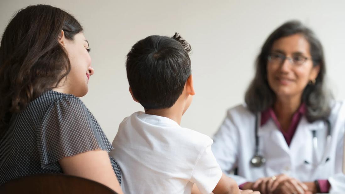 Caregiver with child on their lap, sitting across from healthcare provider, talking