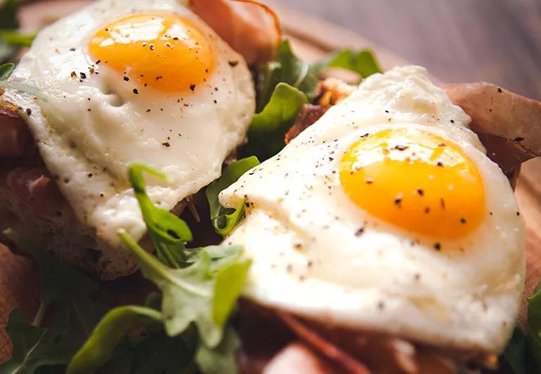 Fried eggs sunny side up, ham and arugula