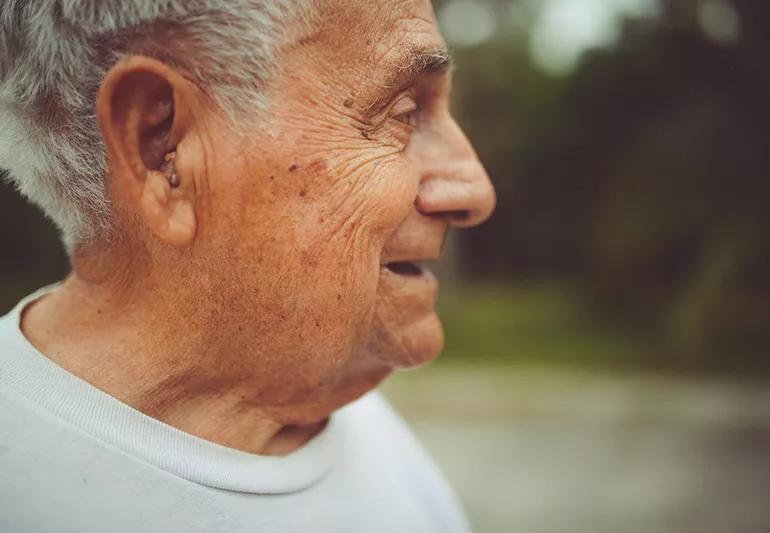 Profile of an elder man wearing an in-the-ear hearing aid