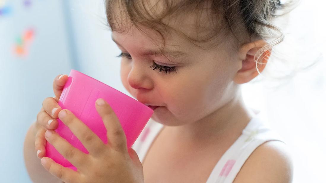 Toddler drinking from a pink cup