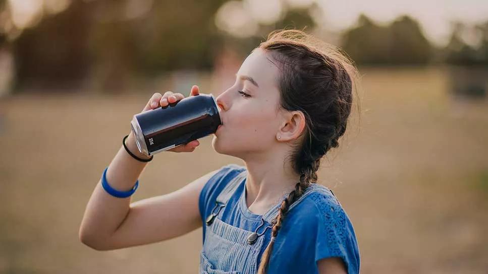 Young female teen drinking canned beverage outside