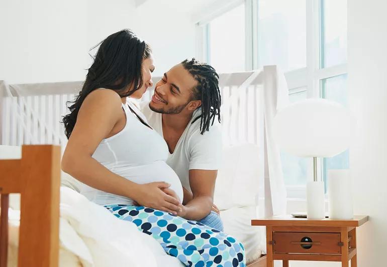 Pregnant woman and man cuddling in bed