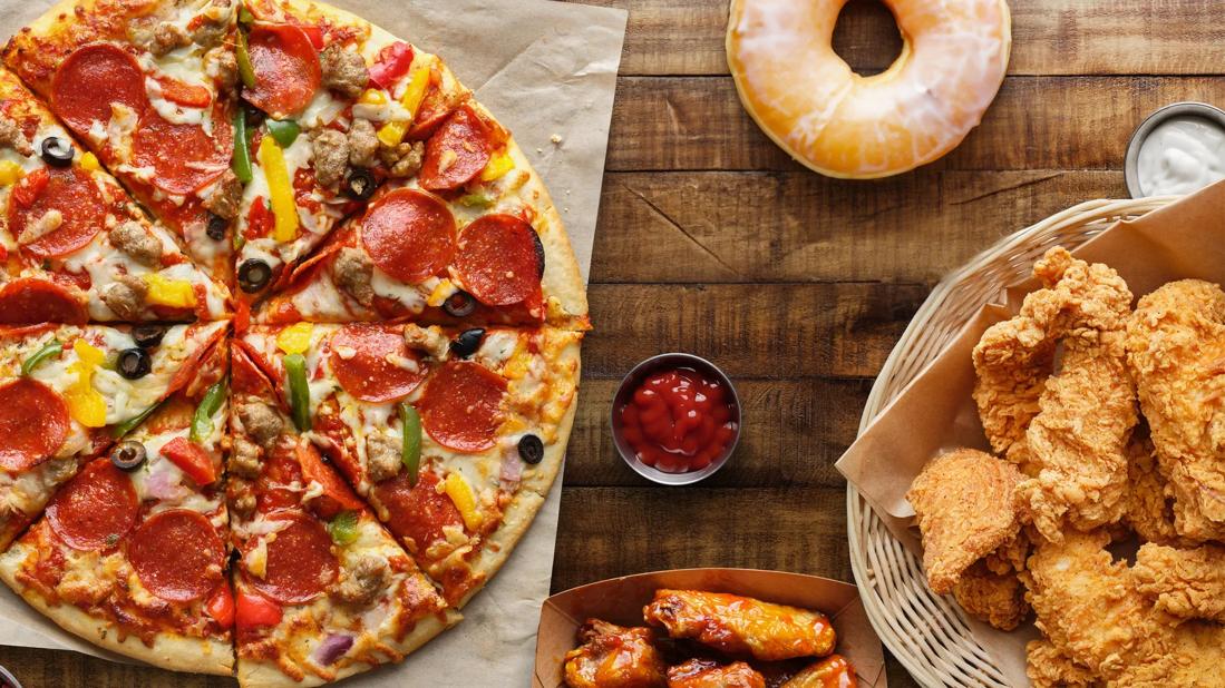 Pizza, donut, chicken wings and fried chicken on wooden table