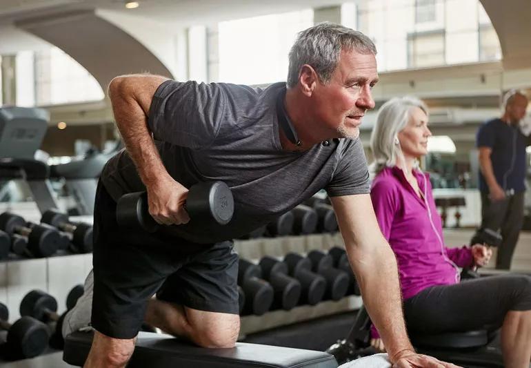 Elderly man lifting weights in a gym