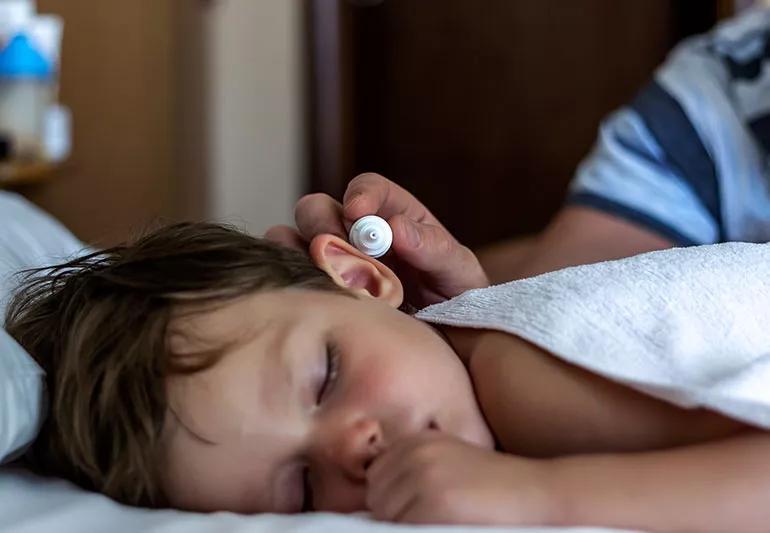 An adult putting ear drops in a child's ear