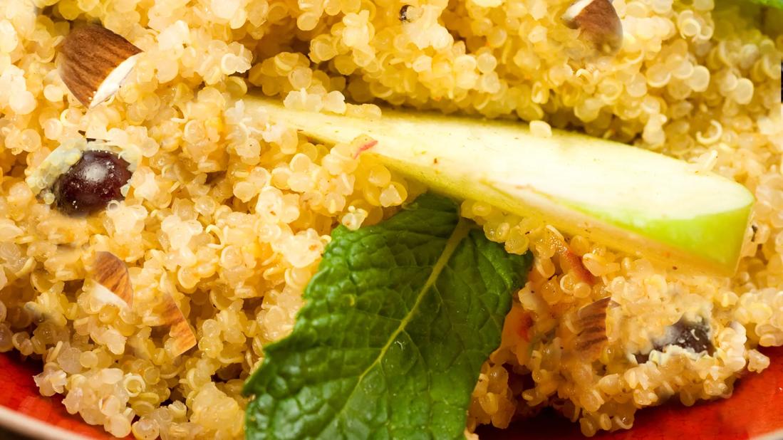 A plate of quinoa and apple salad, with mint leaves and almonds