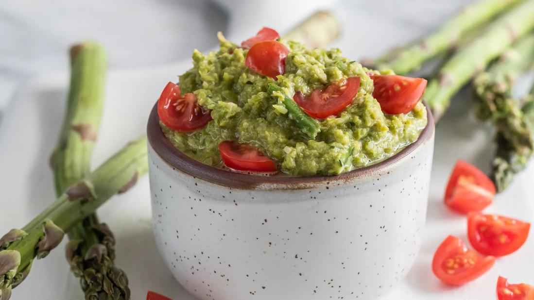 Mexican aparagus dip with diced tomatoes in a small bowl