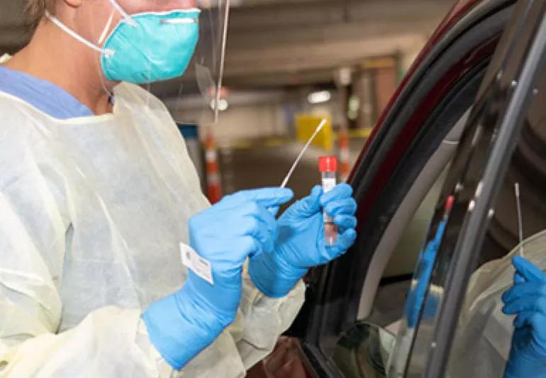 Nurse taking swab from patient to test for COVID-19