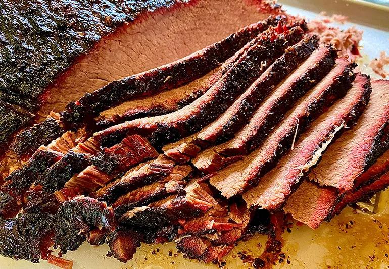 Smoked roast beef is sliced on a cutting board.