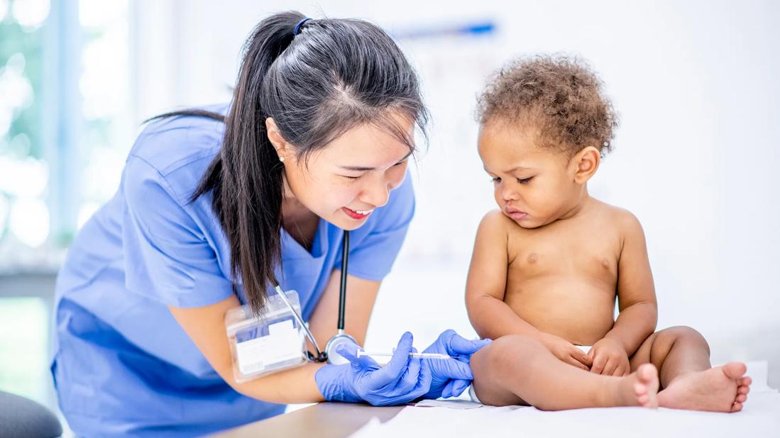 Baby receiving a shot in their leg by healthcare provider