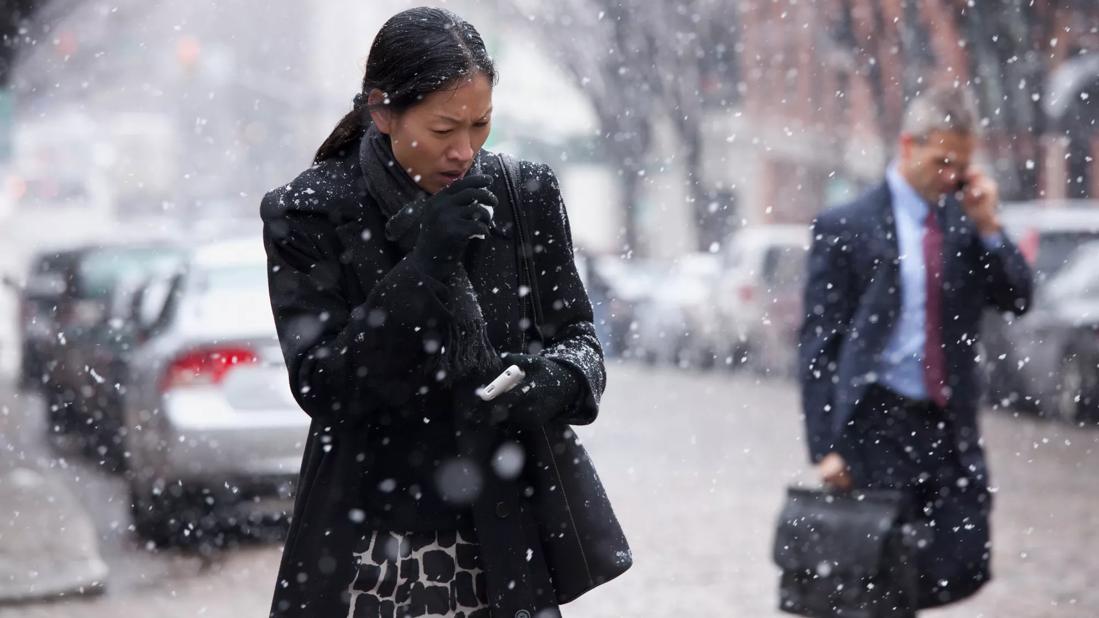 Woman outside in coat during snowy weather covering her mouth