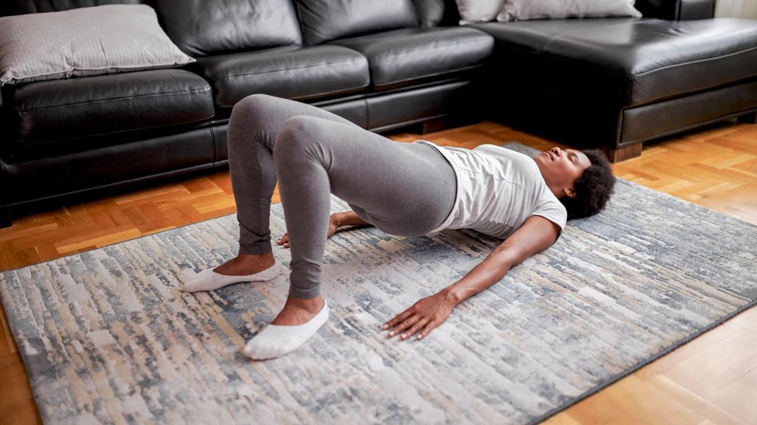 Person lying on floor in living room doing pelvic floor exercise