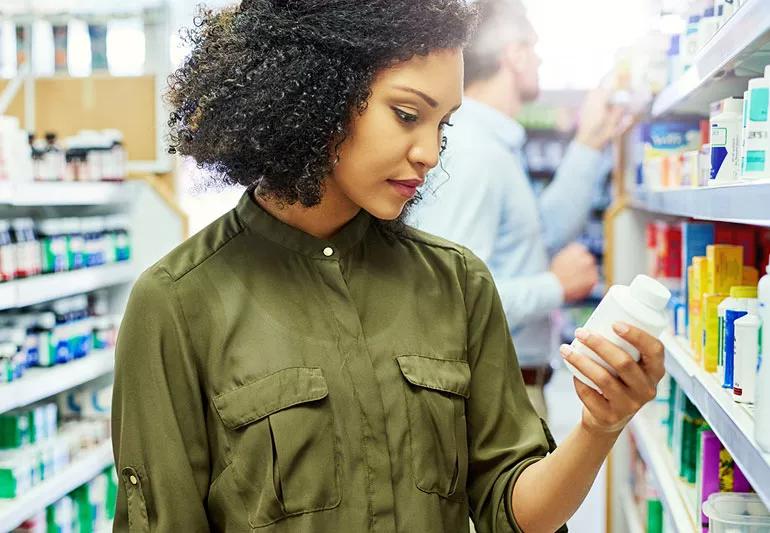 Woman reading medication contents and side effects at store