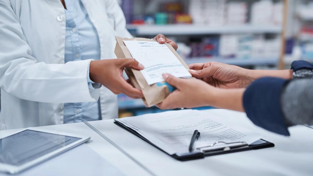 Pharmacist handing medication to patietn