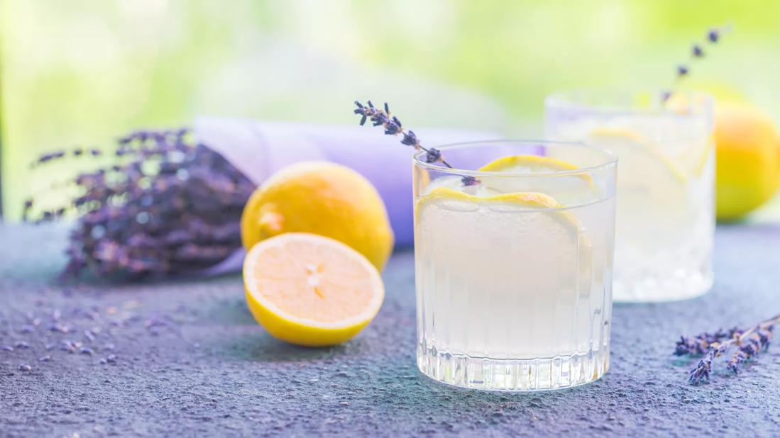 Glasses of lemonade with lavendar sprig, ice and lemons, lavendar on the table