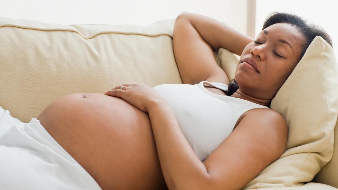 Pregnant person sleeping on back on the couch