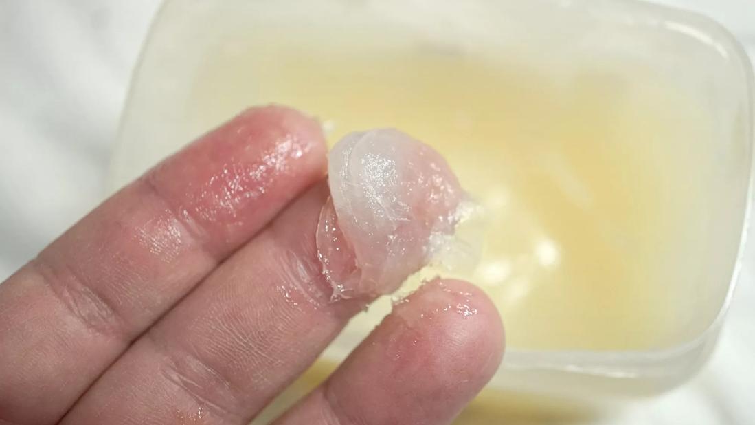 Fingers with globs of petroleum jelly above container