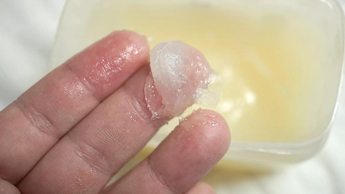 Fingers with globs of petroleum jelly above container