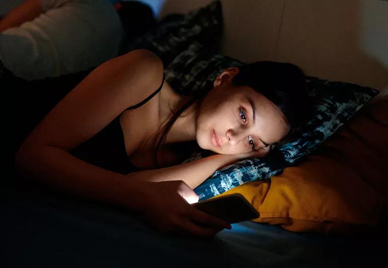 woman using smartphone in bed at night