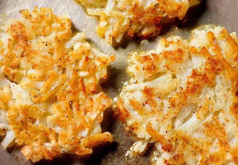 A closeup of potato latkes in a frying pan