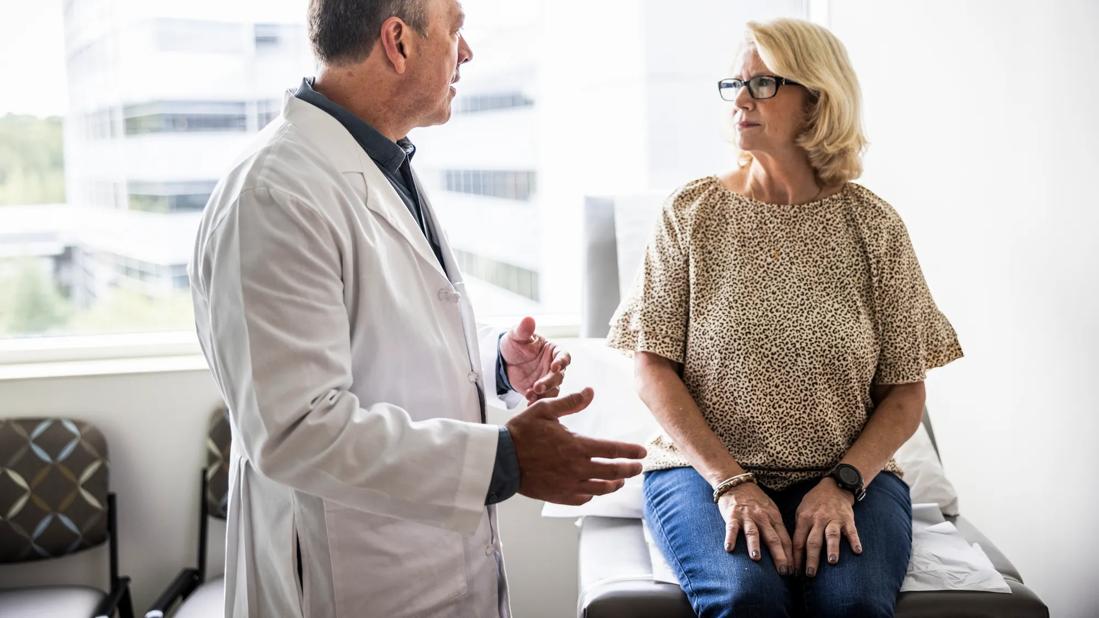 Healthcare provider talking to person sitting on exam table in medical office