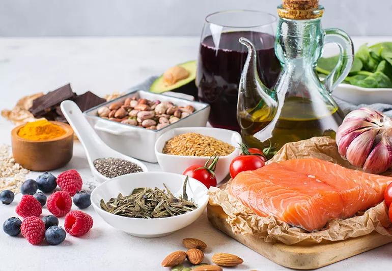 A collection of foods like berries, salmon, almonds, garlic and olive oil