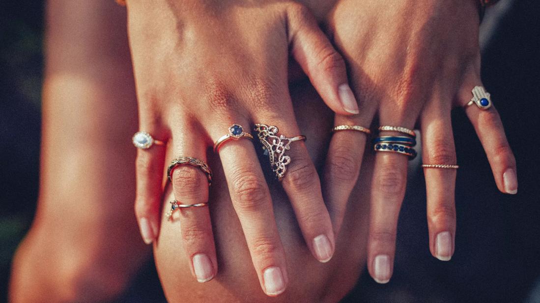 Hands showing many metal rings on the fingers.