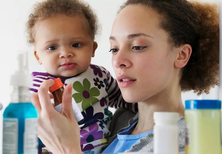 Mother and child checking cough syrup in their medicine cabinet.