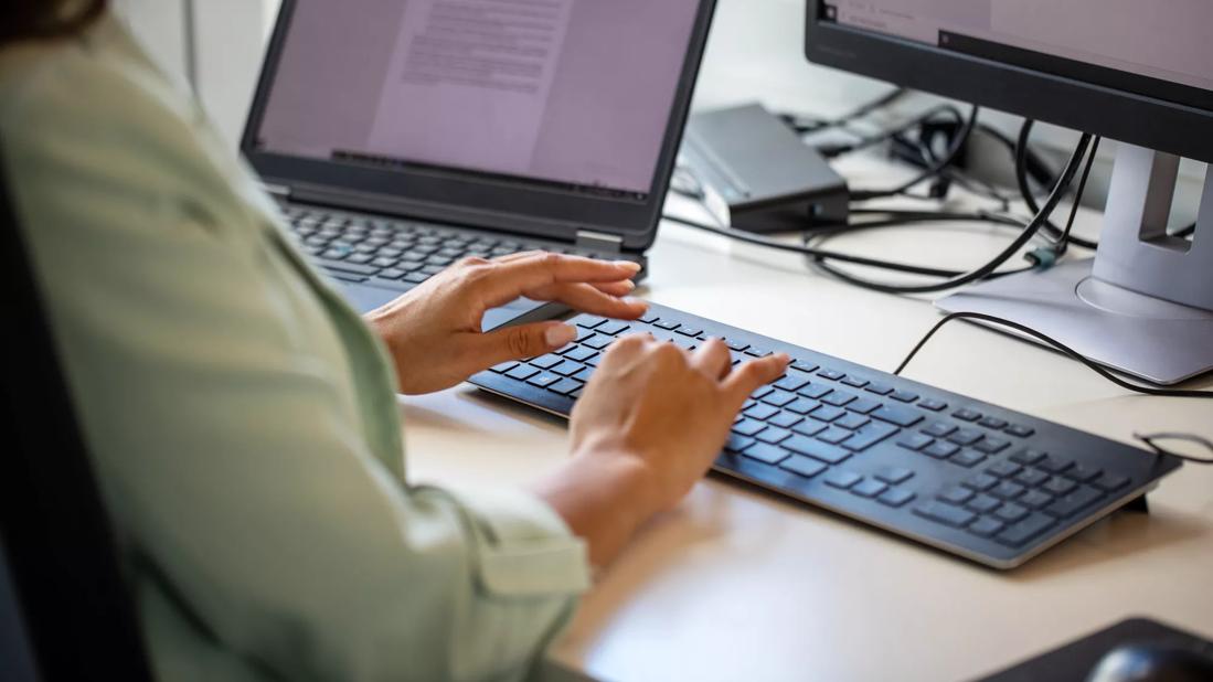 Person typing on keyboard in front of computer screen