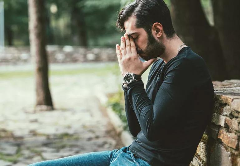 Generation Z aged man stressed on park bench