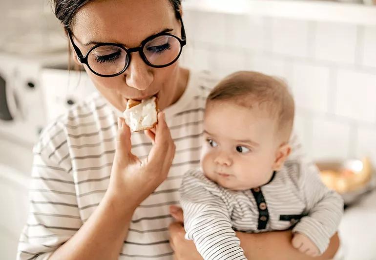 Woman snacking with baby in arms