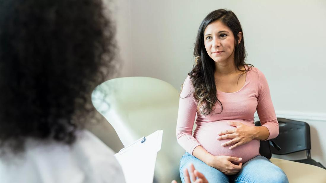 Pregnant person talking with caregiver in medical office