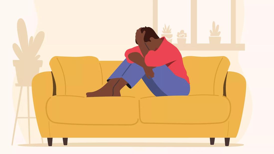 An illustration of a person sitting on a couch with their head in their hands