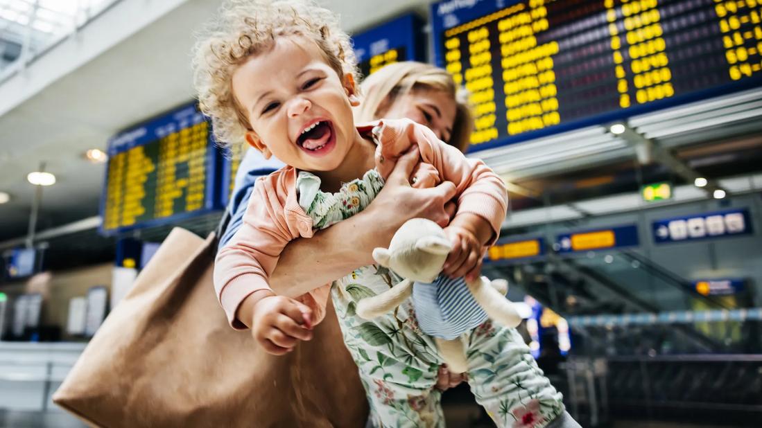 Laughing, happy baby being carried by caregiver in airport