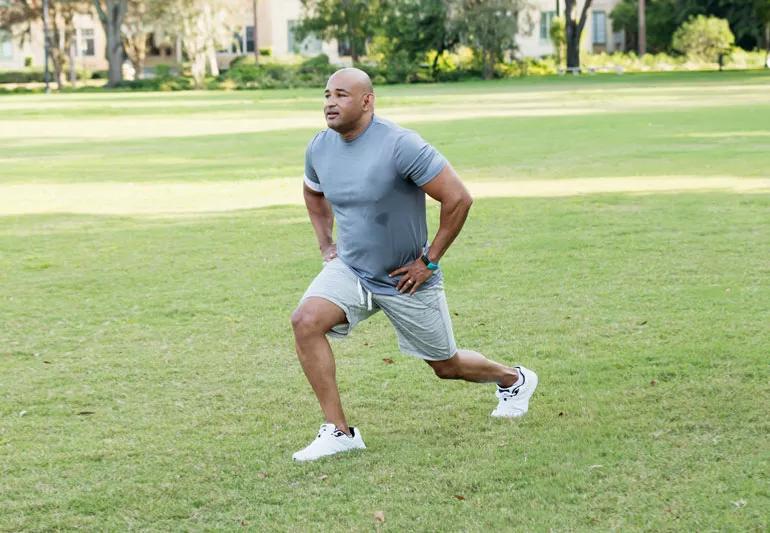 man dynamic stretching doing walking lunges