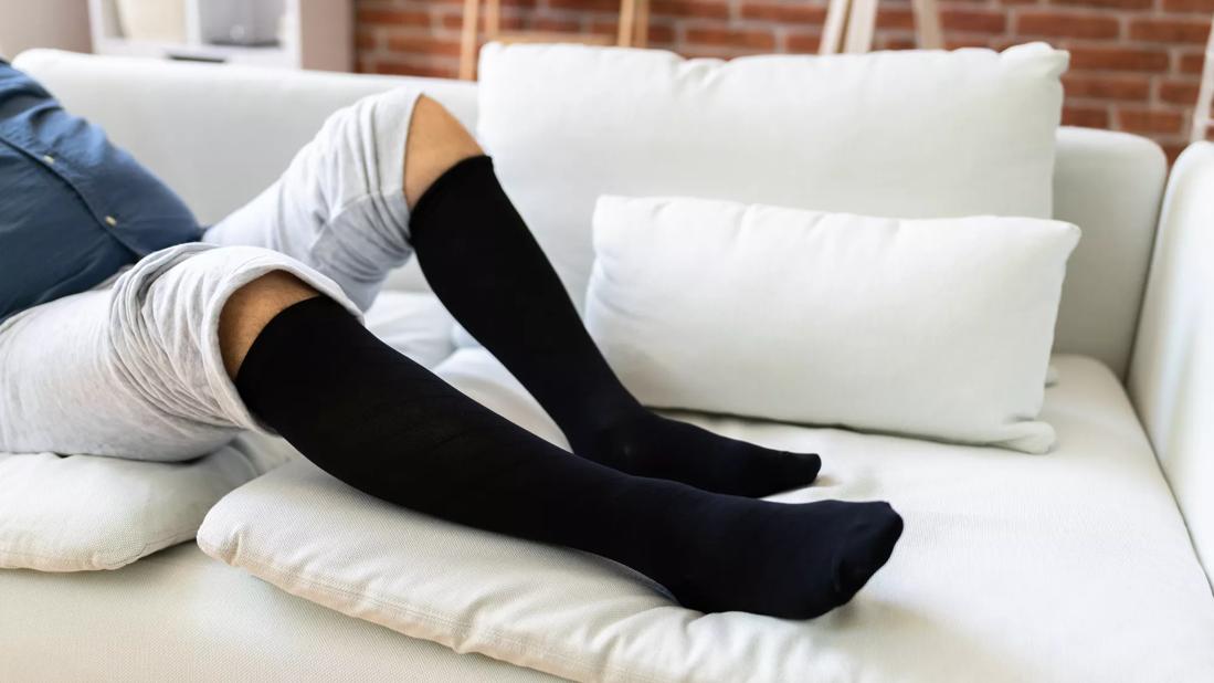 Person reclining on couch wearing compression socks